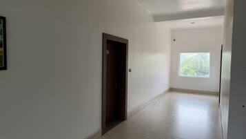 A hallway with a door, a window, and a tiled floor.