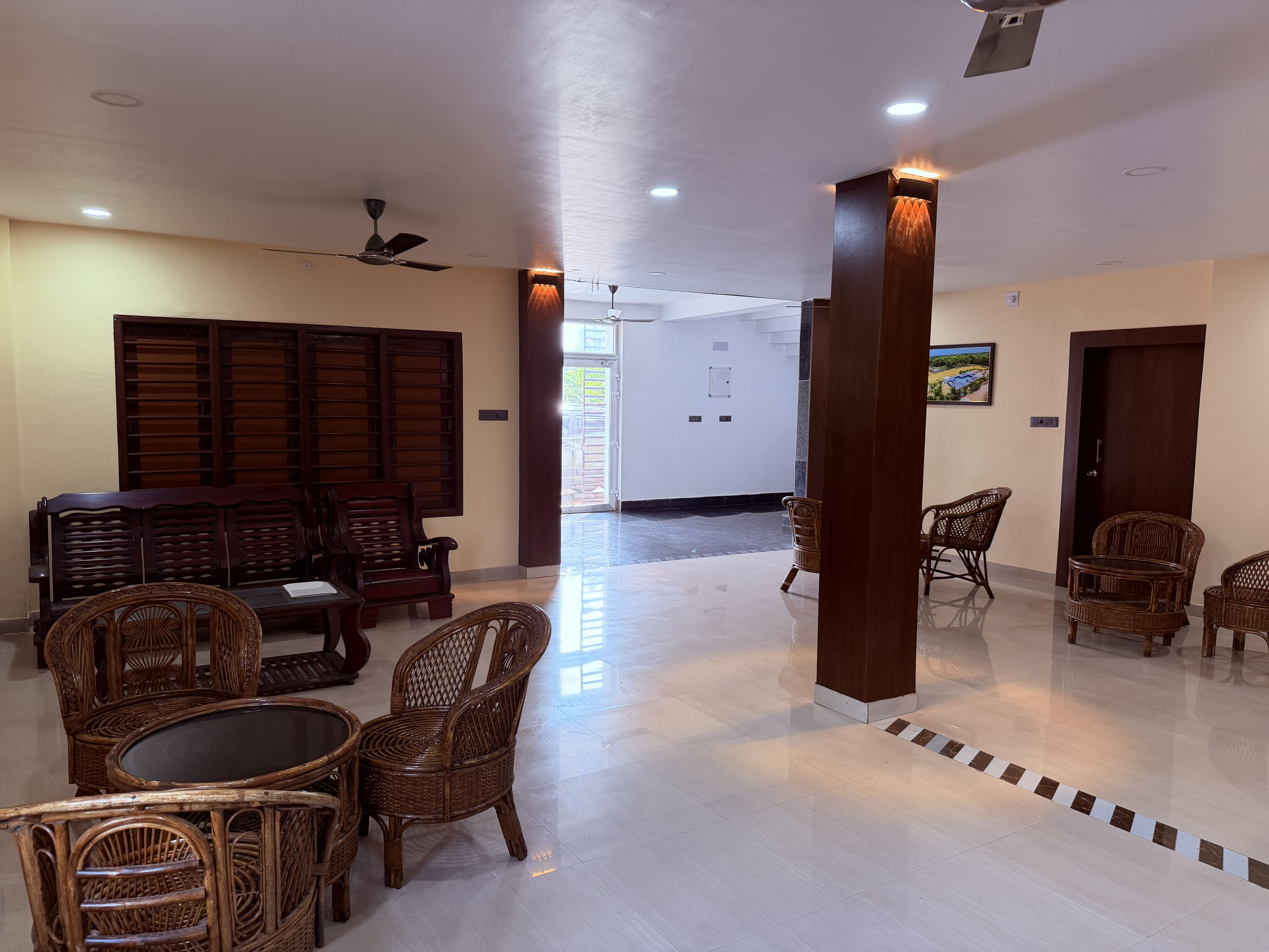 A spacious lobby with a high ceiling, ceiling fans, and a seating area with wicker furniture.
