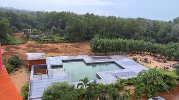 A swimming pool with a surrounding deck, surrounded by dense greenery and trees.