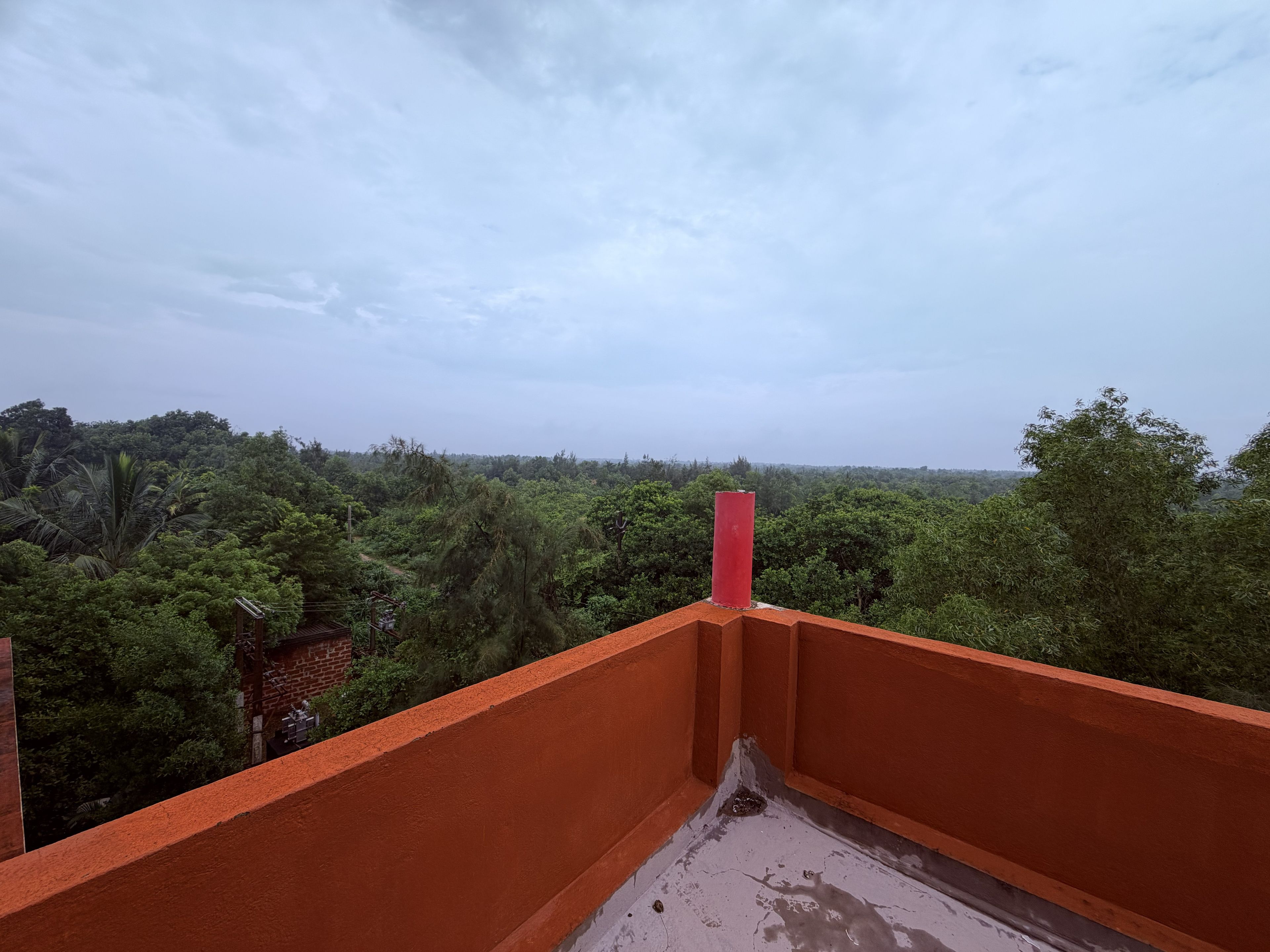Un balcone con vista su una vegetazione lussureggiante e un cielo nuvoloso.