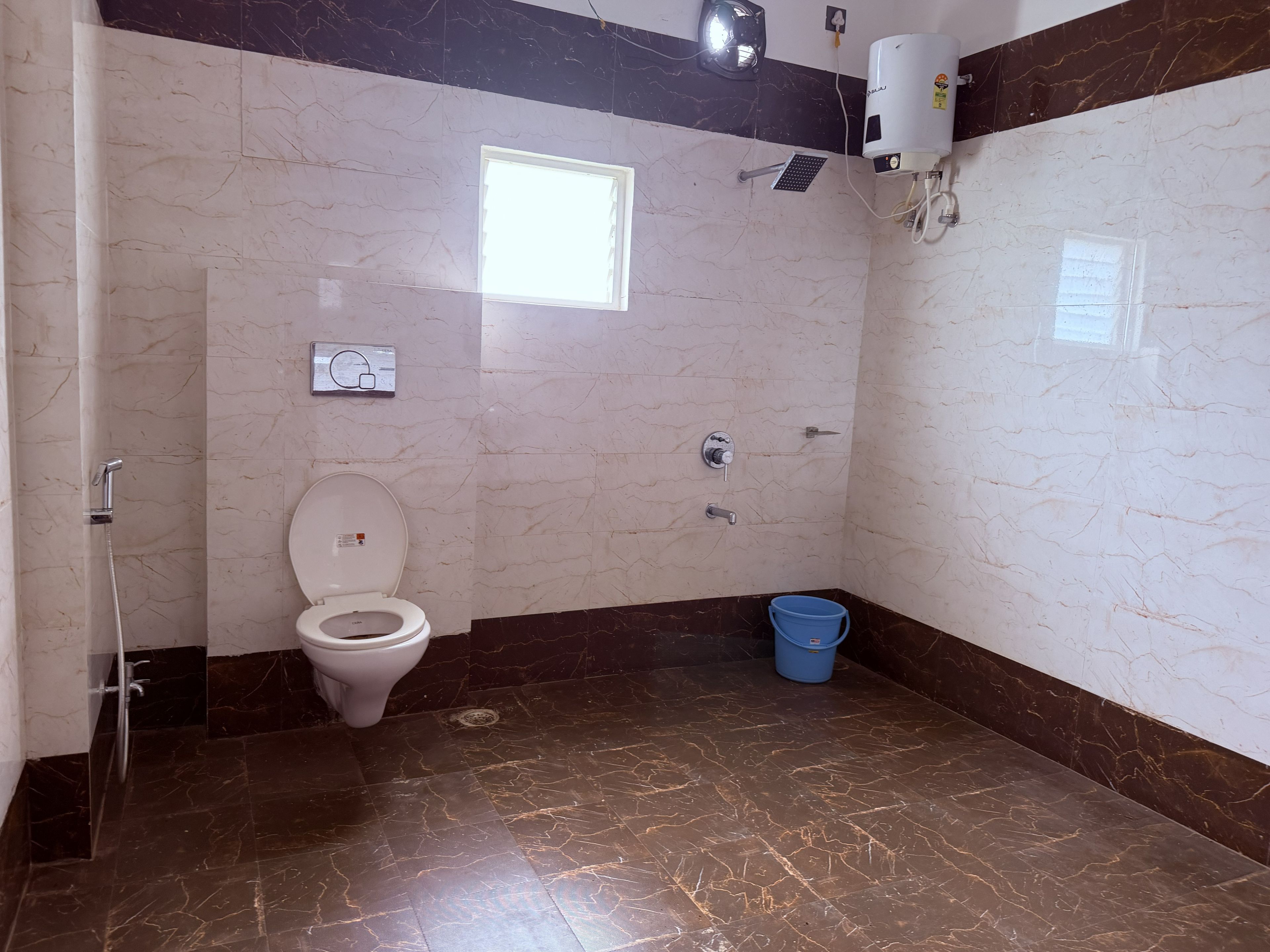 A bathroom with a toilet, shower, and a blue bucket.