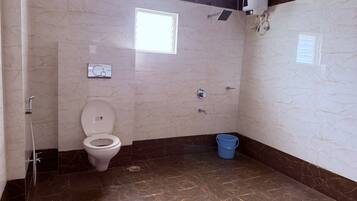 A bathroom with a toilet, shower, and a blue bucket.