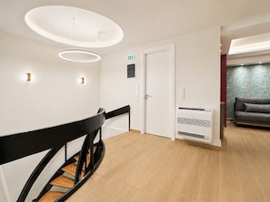 A modern interior with a staircase, a flat-screen TV, and a sofa in a lounge area. - Galleria The House by ΜΡS (Athina)