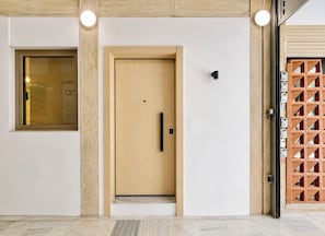 A modern interior with a wooden door, a glass window, and a wall-mounted light fixture. - Galleria The House by ΜΡS (Athina)