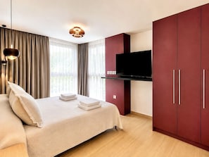 Une chambre à coucher moderne avec un lit, des rideaux, une télévision et une armoire.