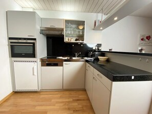 Eine kleine Küche mit weißen Schränken, einer schwarzen Arbeitsplatte und einem eingebauten Backofen.