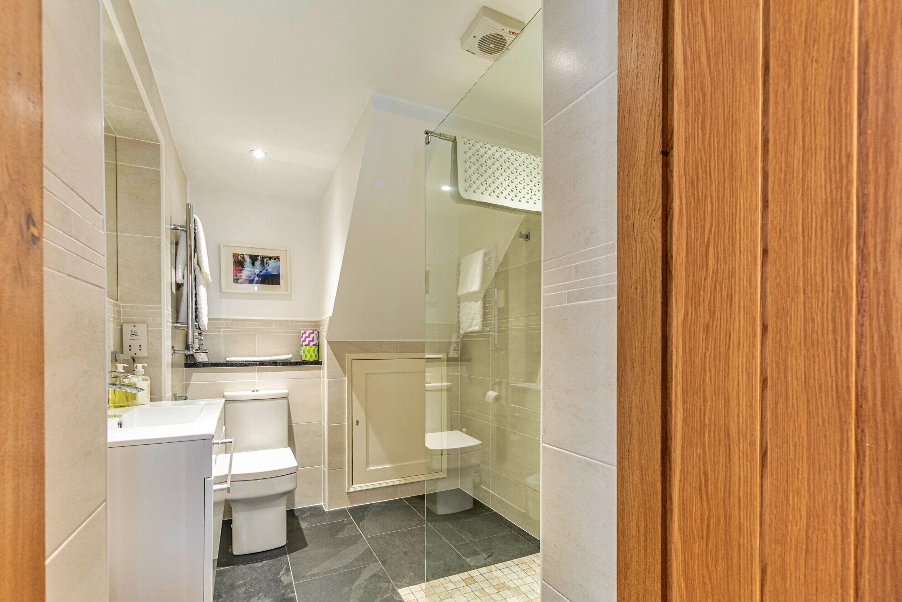 Een moderne badkamer met douche, toilet en wastafel.