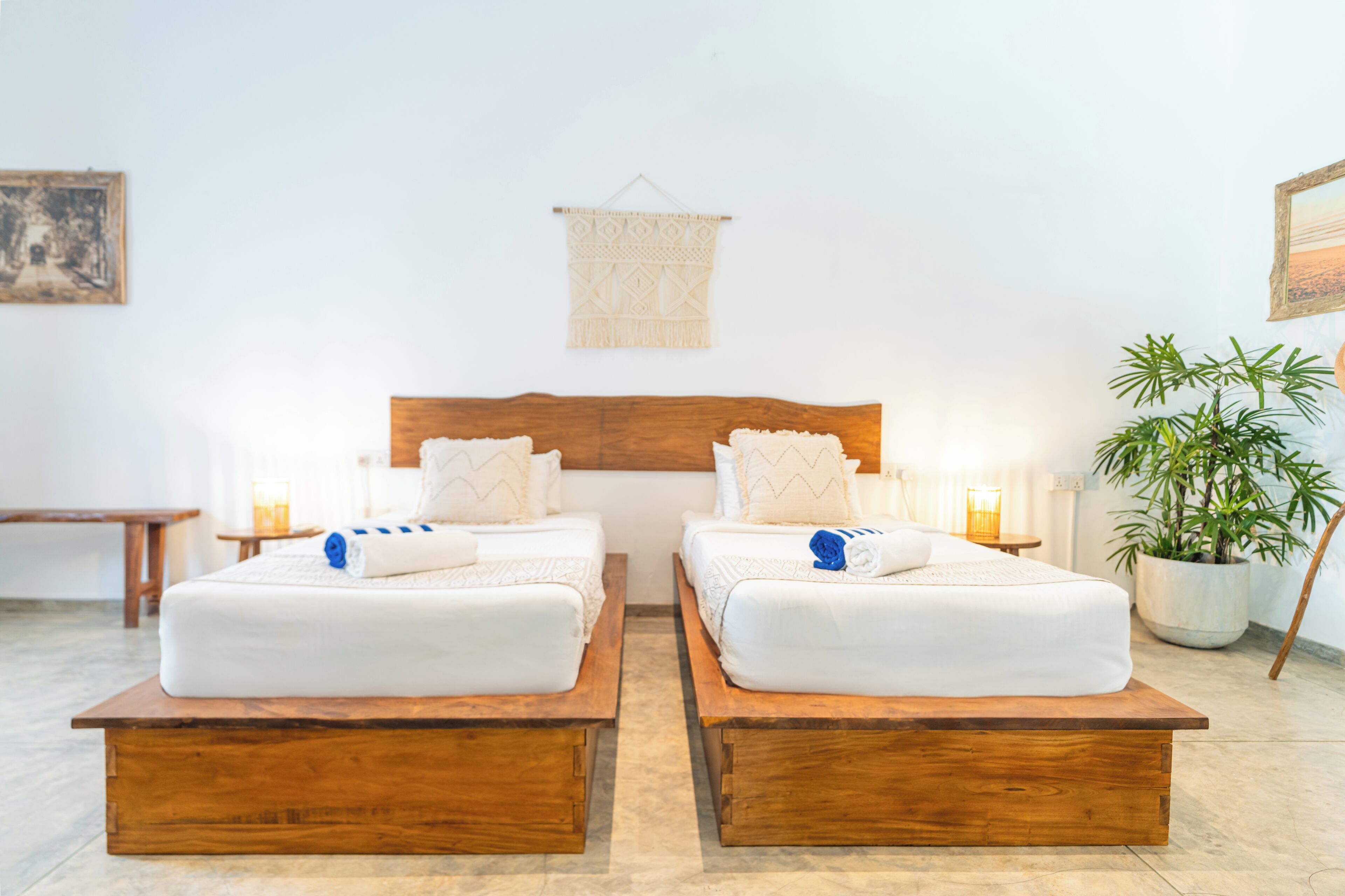 A hotel room with two beds, wooden headboards, and a hanging macrame wall hanging.