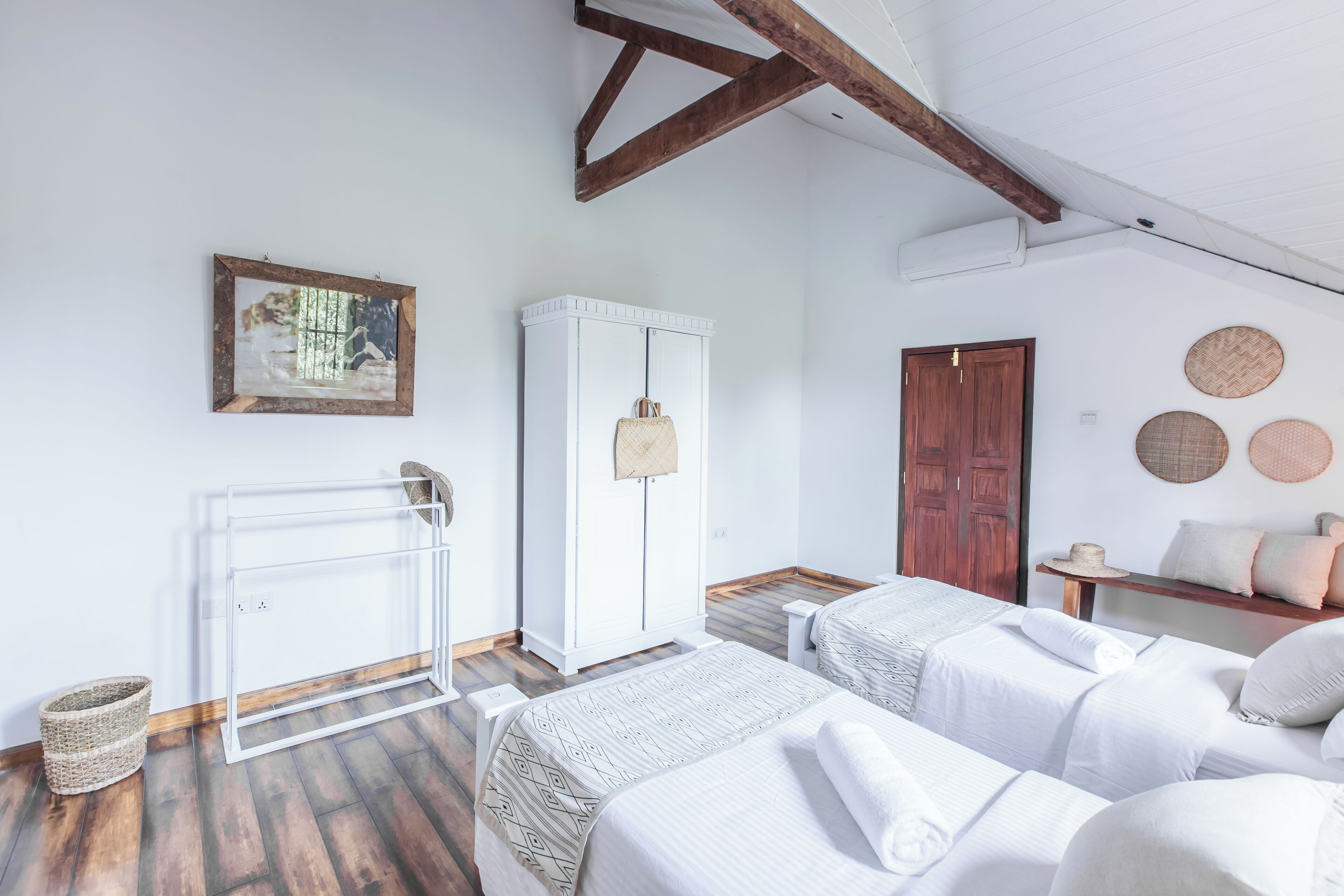 A bedroom with two beds, a wardrobe, a radiator, and a wooden ceiling.