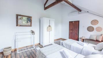 A bedroom with two beds, a wardrobe, a radiator, and a wooden ceiling.
