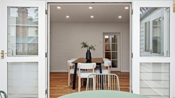 A dining area with a table, chairs, and a vase of flowers. - South Hobart Designer Retreat (South Hobart)
