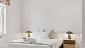 A bedroom with a bed, two bedside tables, two lamps, and a window. - South Hobart Designer Retreat (South Hobart)