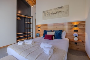Ein Hotelzimmer mit einem Bett, einem Holzkopfstück, einem an der Wand befestigten Regal und einem Gemälde.
