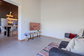 Ein modernes Wohnzimmer mit einer Couch, einem Couchtisch und einem an der Wand befestigten Fernseher.
