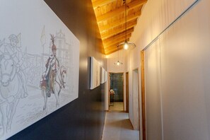 Ein Korridor mit Holzbalkendecke, einer Hängeleuchte und einer Wand mit einer großen Skizze.