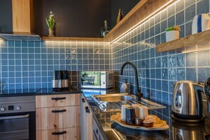 Eine moderne Küche mit blauen Fliesen, Edelstahlgeräten und Holzschränken.