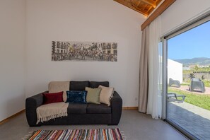 Ein Wohnzimmer mit einer Couch, einem farbenfrohen Teppich, einem großen Fenster und einem Gemälde an der Wand.