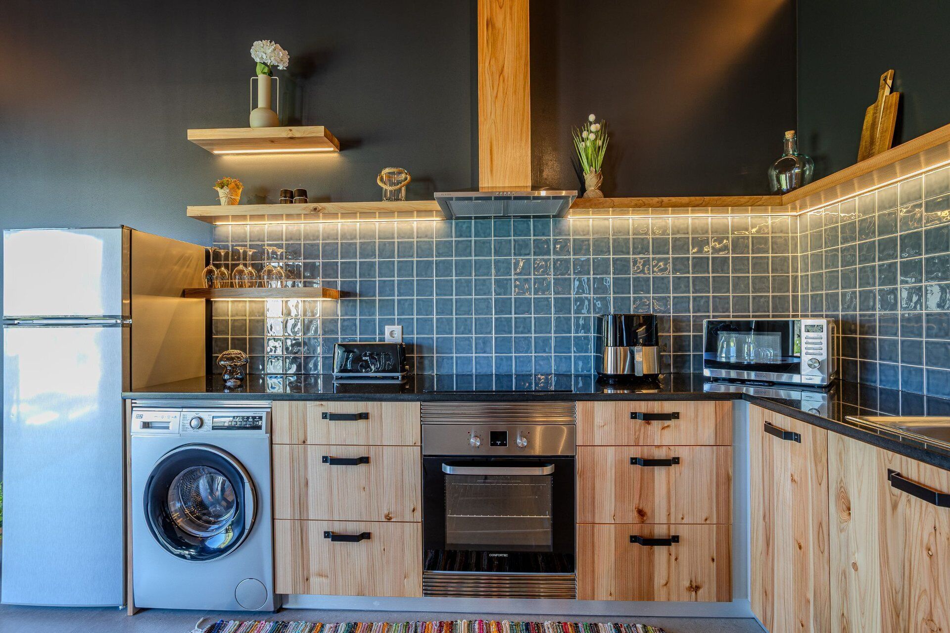 Una cocina moderna con lavadora, horno, microondas y varios electrodomésticos.