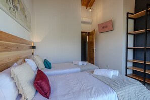 Une chambre d’hôtel avec deux lits, une tête de lit en bois, un climatiseur fixé au mur, une pancarte indiquant « CHAMBRE PRÊTE » et une étagère.