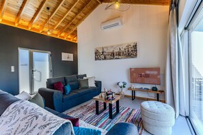 A modern living room with a blue sofa, a coffee table, and a television displaying 'GUEST READY'. - Guestready - Casa do Lanceiro by Cavalhadas House (Ribeira Grande)