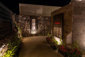 A stone wall with a metal gate, a paved pathway, and red flowers. - Guestready - Casa do Lanceiro by Cavalhadas House (Ribeira Grande)