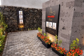 A stone wall with a signboard displaying 'Cavalhadas House' and 'Via Turística' along with images of traditional figures.