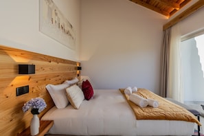 A hotel room with a wooden headboard, a bed with white bedding, a red pillow, a vase with flowers, and a window with curtains. - GuestReady - Casa do Cavaleiro by Cavalhadas House (Ribeira Grande)