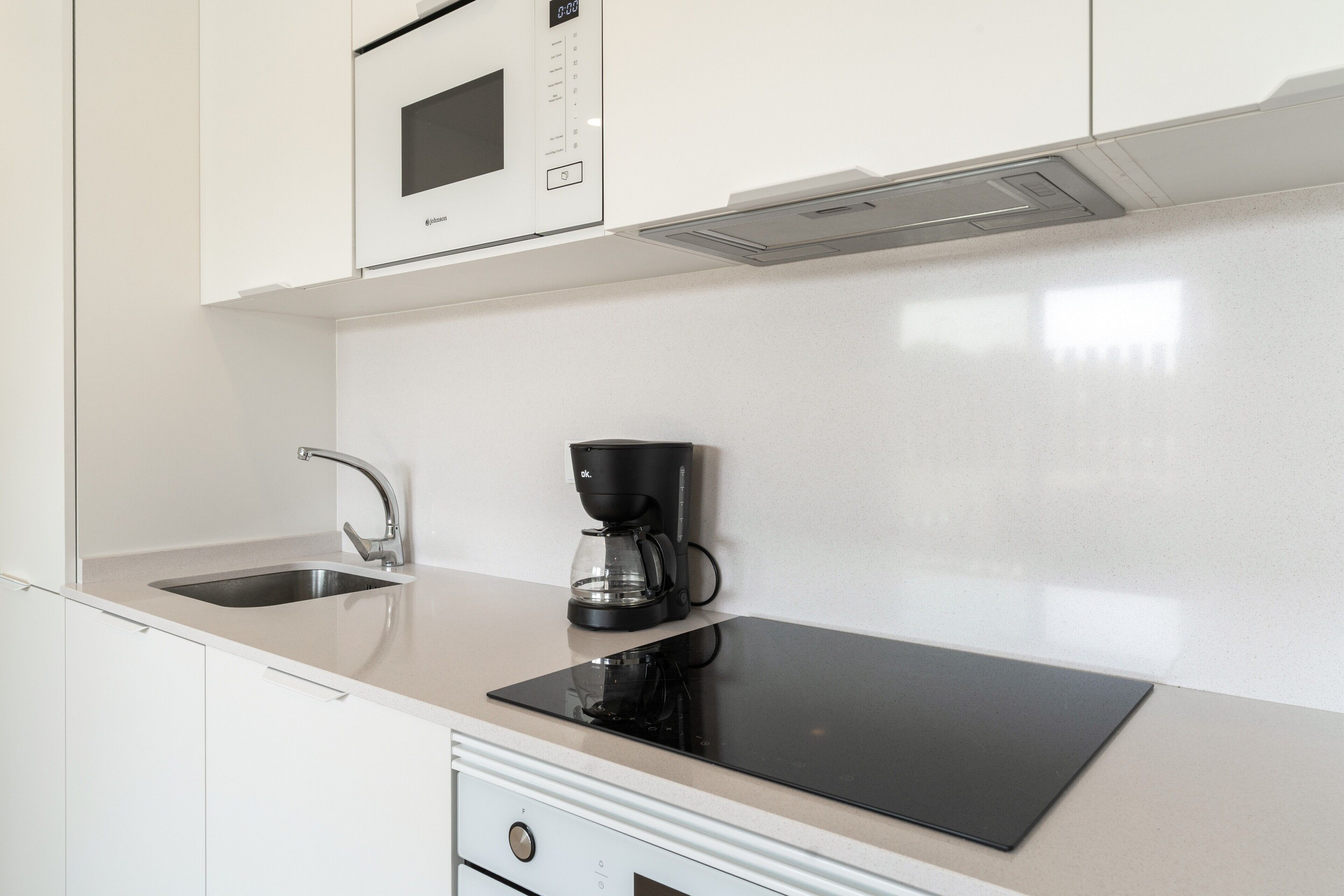 Una cocina moderna con microondas incorporado, cafetera y una encimera elegante.