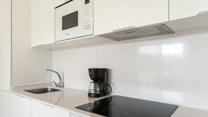 Een moderne keuken met een ingebouwde magnetron, een koffiezetapparaat en een strak aanrecht.
