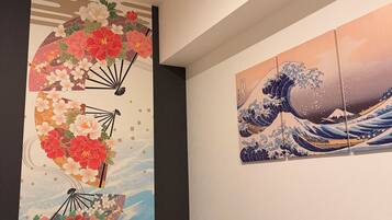Un comedor con una mesa de madera, dos velas y dos obras de arte en la pared que representan escenas tradicionales japonesas.
