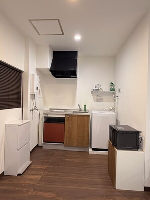 Una cocina compacta con lavavajillas integrado, microondas y un refrigerador pequeño.