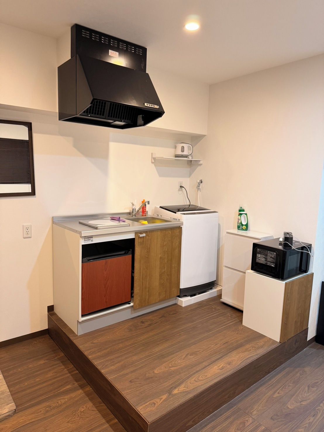 A compact kitchen with a built-in dishwasher, a microwave, and a small refrigerator.