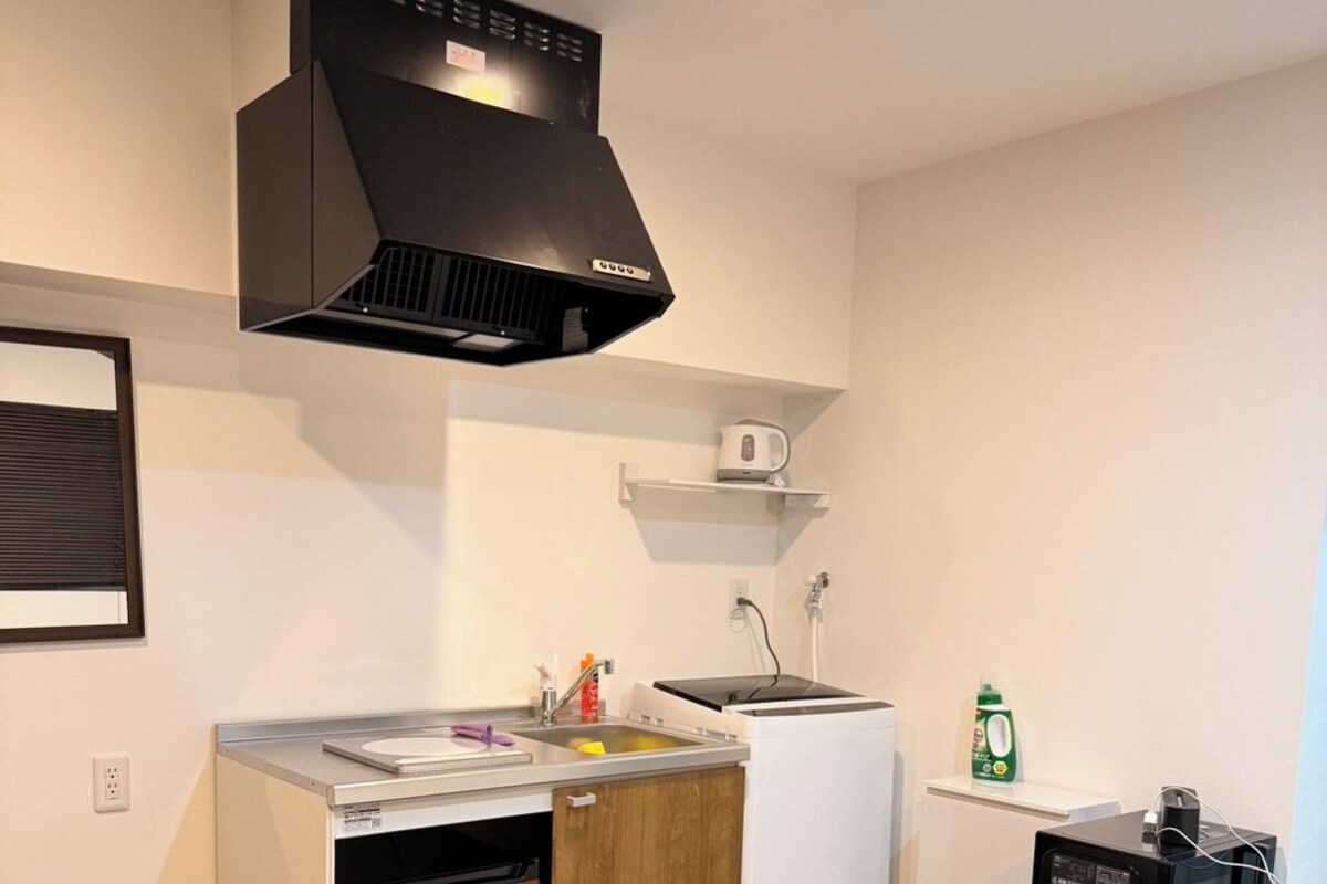 Cocina compacta con lavavajillas integrado, microondas y refrigerador pequeño.
