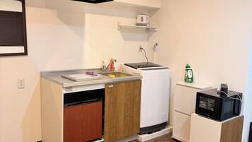 A compact kitchen with a built-in dishwasher, a microwave, and a small refrigerator.