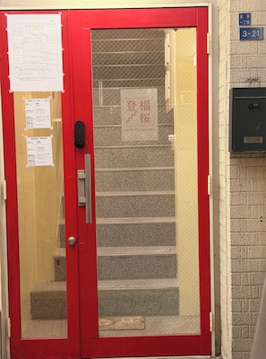 A red door with a glass panel, a staircase, and a sign that reads 'DENG FU SAKURA'. - To-Fu-rou (Osaka)