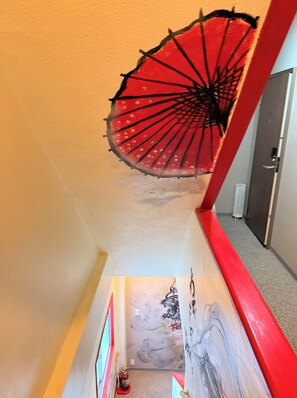 Una escalera con barandilla roja y un adorno de paraguas rojo en la pared.