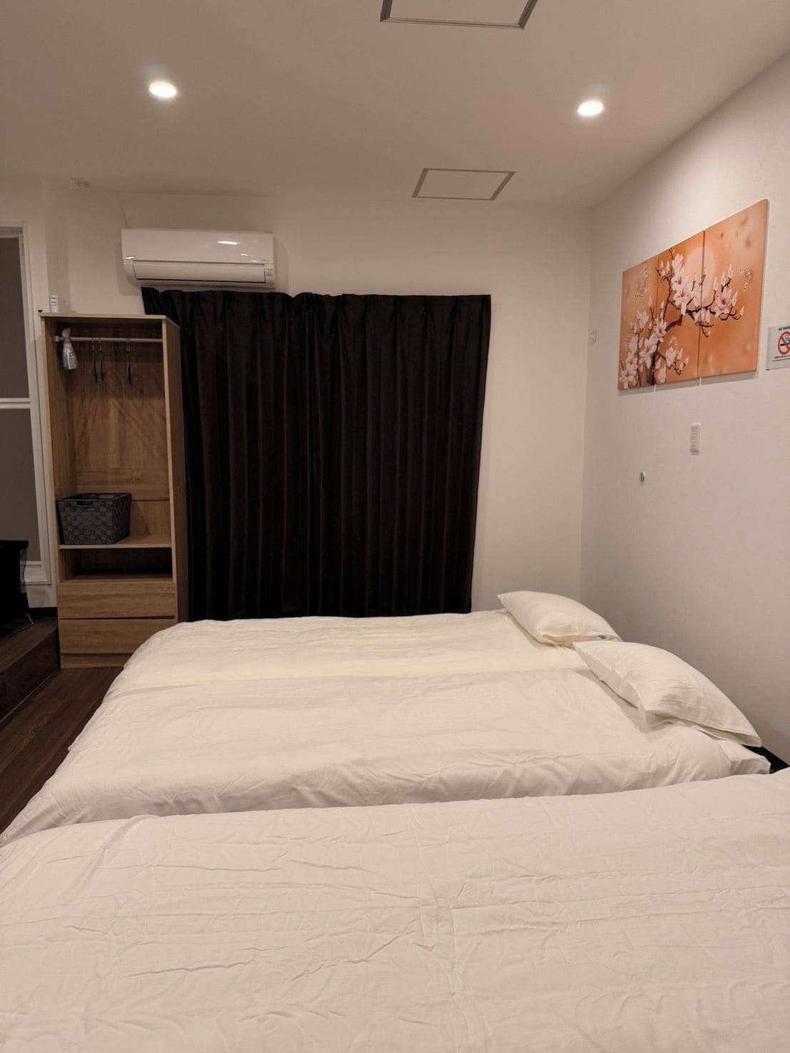 Un dormitorio con cama, armario, zona de ducha y aire acondicionado instalado en la pared.