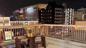 A rooftop terrace with outdoor seating and a city view at night.