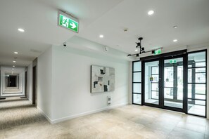 A modern hotel lobby with a long corridor, a glass door entrance, and a security camera. - Brand New Luxury 2 Bedroom Surrey/White Rock (Surrey)
