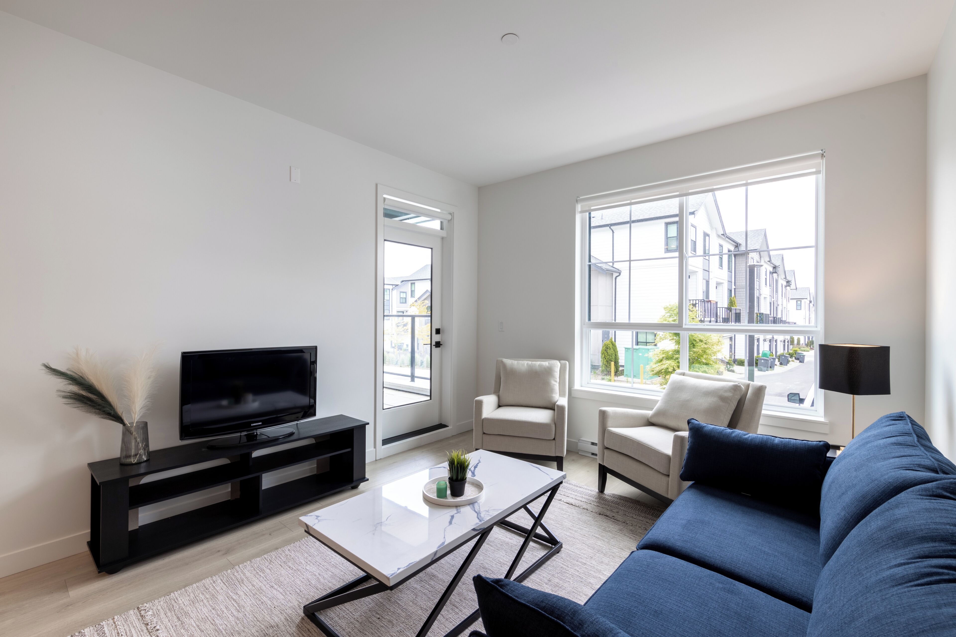 Un salon moderne avec un téléviseur à écran plat, un canapé, une table basse et un fauteuil.