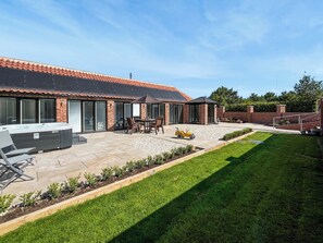 A modern house with a patio, a hot tub, and a small play area. - Rose Blossom Cottage (Benniworth, near Market Rasen)