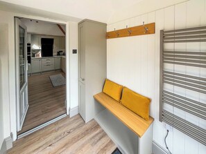 Et moderne interiør med en træbænk, knagerække og et køkken i baggrunden.