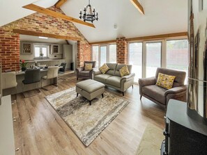 A spacious living area with a kitchen, a dining table, and a fireplace. - Rose Blossom Cottage (Benniworth, near Market Rasen)