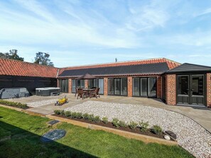 Ein Wohnhaus mit Terrasse, Sitzgelegenheiten im Freien und einer Garage.