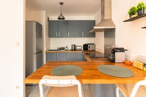 A modern kitchen with grey cabinets, a stainless steel refrigerator, a microwave, and a range hood. - Premium 2-Bedroom Apartment - Genève Express - Train station 200 meters away on foot (Bons-en-Chablais)