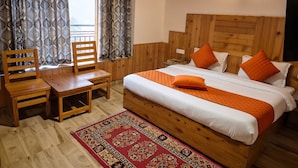 A wooden-paneled room with a bed, a chair, a table, and a patterned rug. - OnlyStay Persimmon Farmstead (Manali)