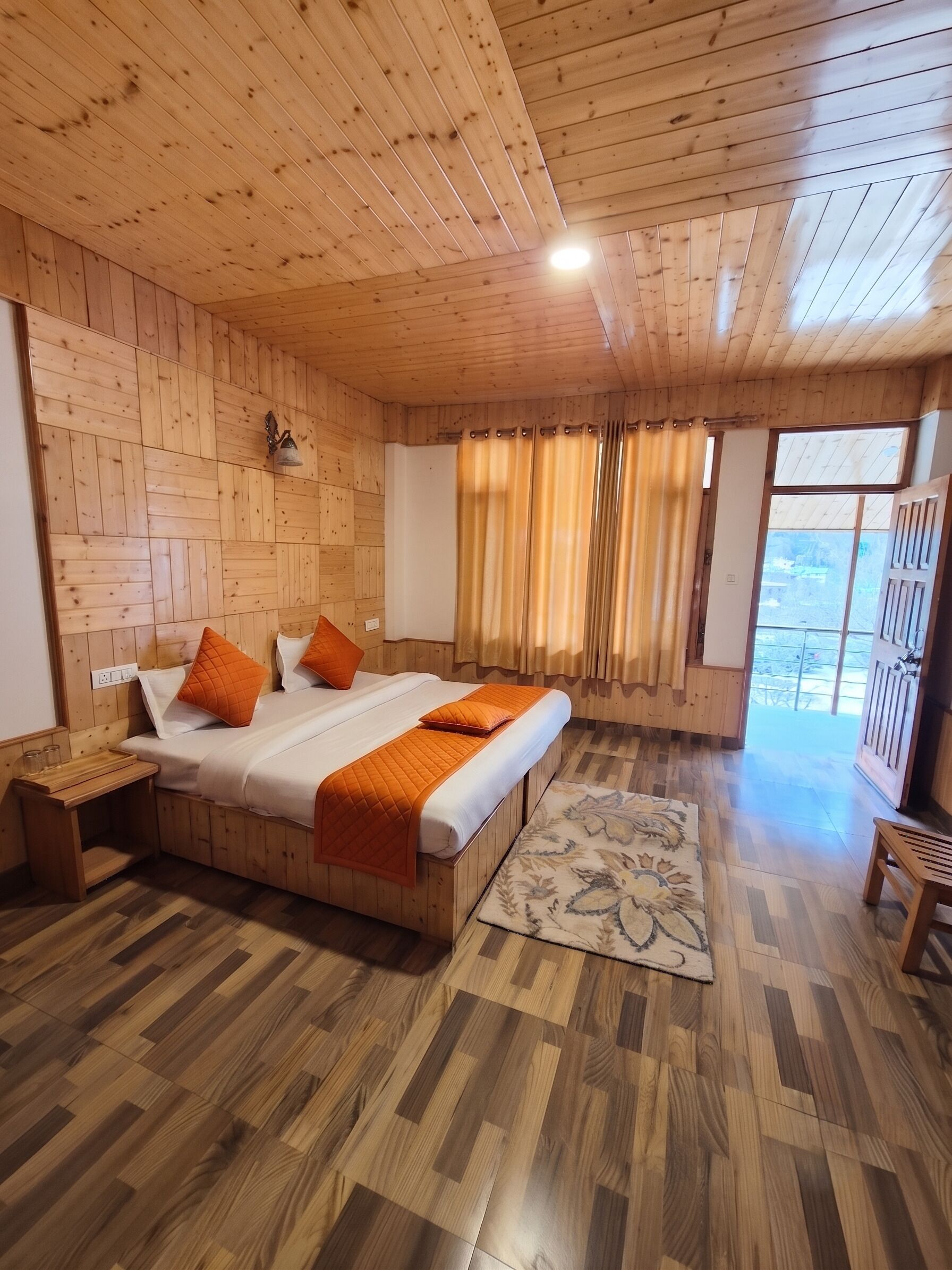 A wooden-paneled room with a bed, a small table, and a view through a window.