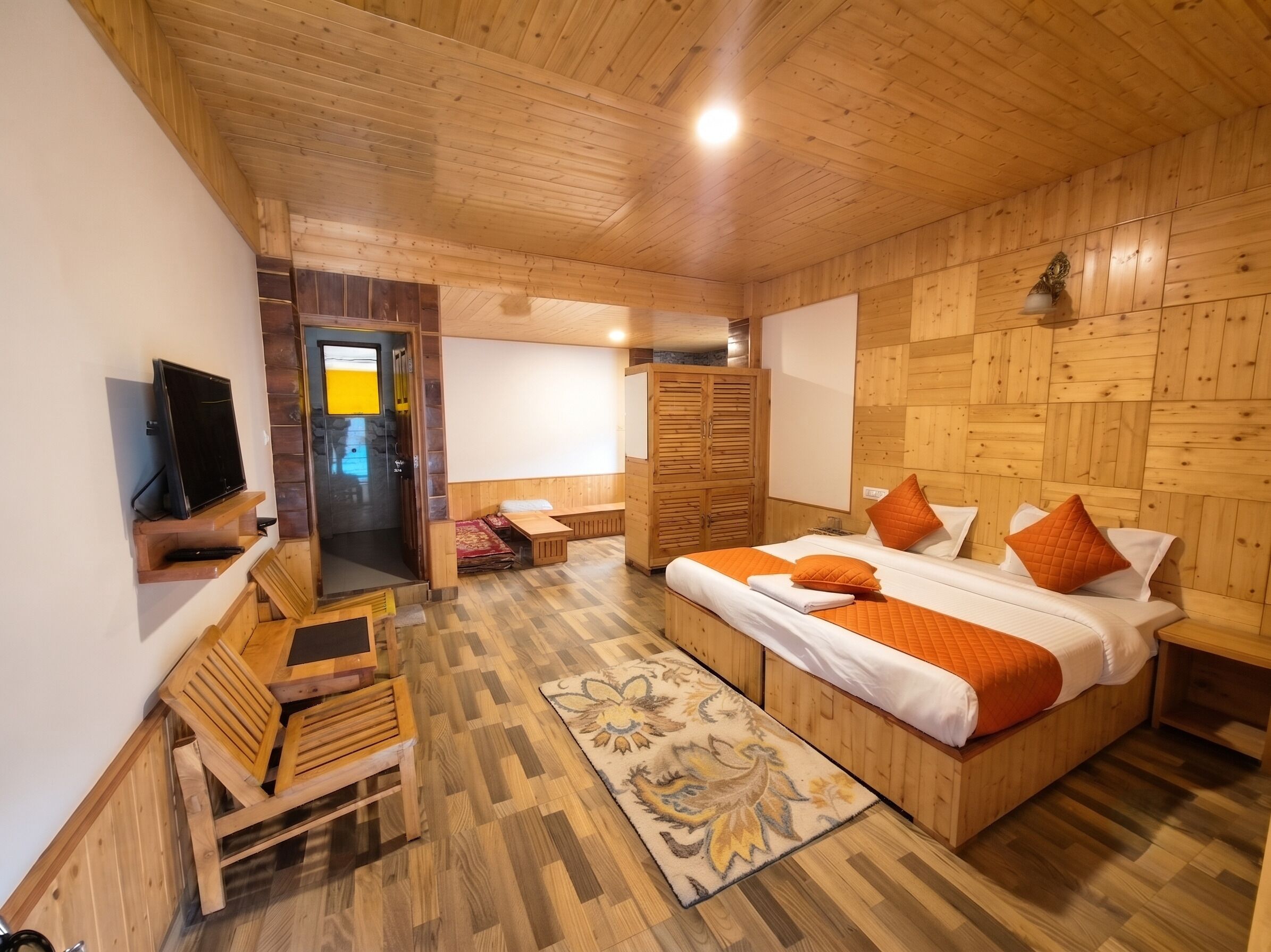 Un intérieur en bois comprenant un lit, un coin salon et un téléviseur.