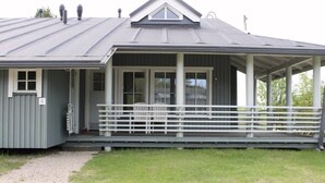 En enplansbyggnad med en överbyggd veranda, en dörr och ett litet fönster.