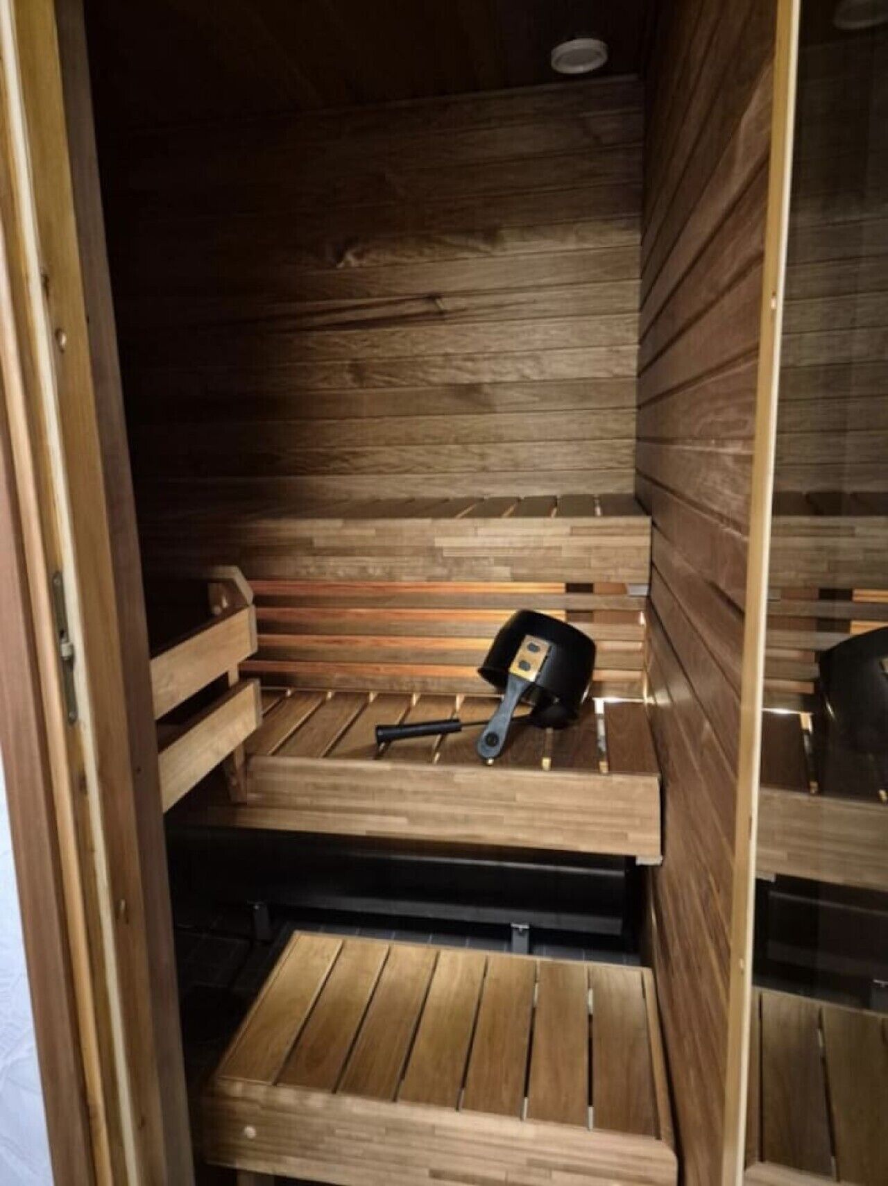 A sauna with wooden benches and a bench with a sauna brush.